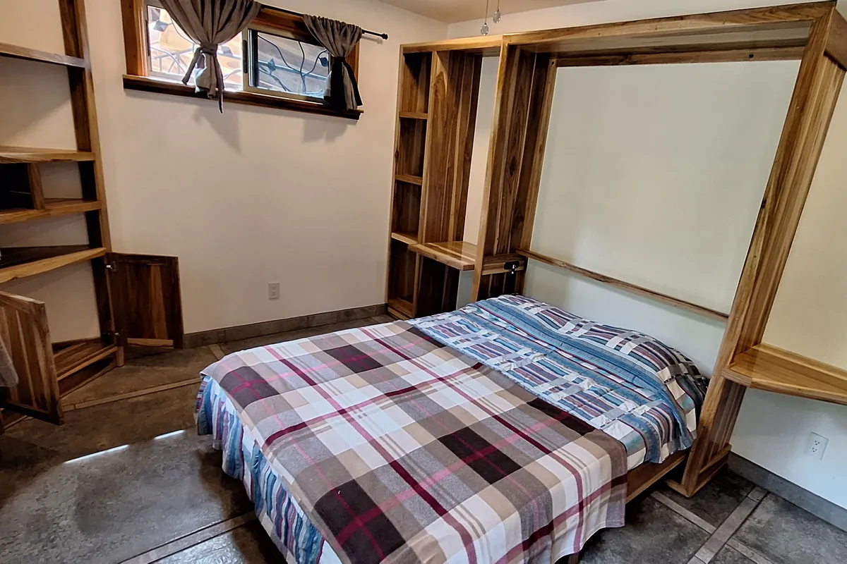 Cama abatible en madera, abierta, con libreros a los lados