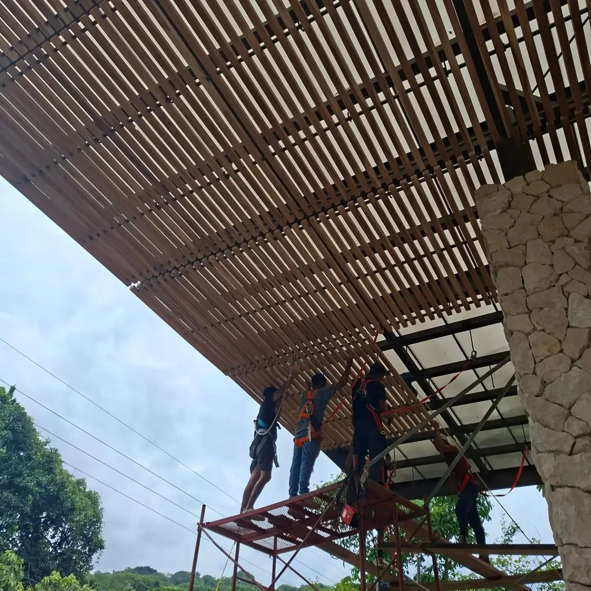 Nuestro equipo, con arneses de seguridad, instalando desde un andamio los paneles de teca del pórtico