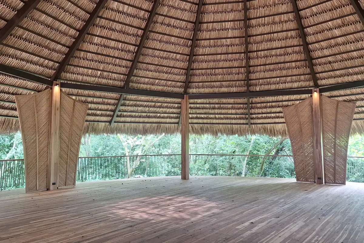 Rancho con techo de palma y piso de madera sobre el bosque